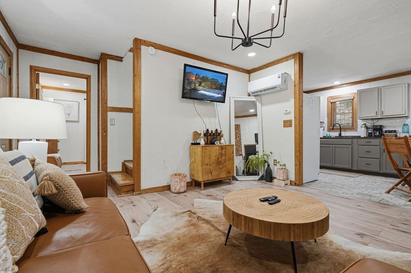 Unwind in your stylish living space with warm leather seating, natural wood accents, and modern amenities including AC and flatscreen TV for perfect comfort.