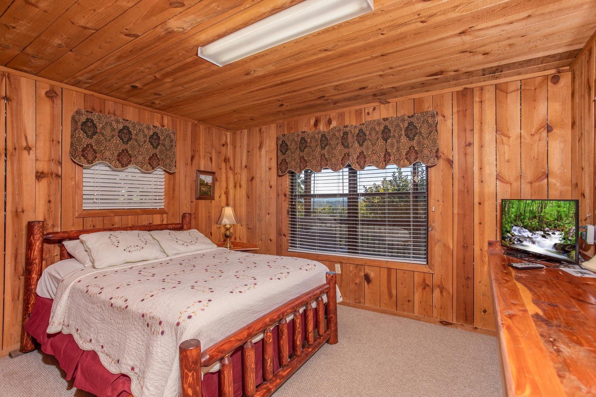 A queensized log bed and a television at Apple View, a 2 bedroom cabin rental located in Pigeon Forge