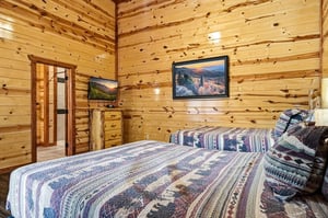 Wake up surrounded by warm knotty pine walls in this cozy cabin bedroom, where rustic charm meets modern comfort with your private TV.