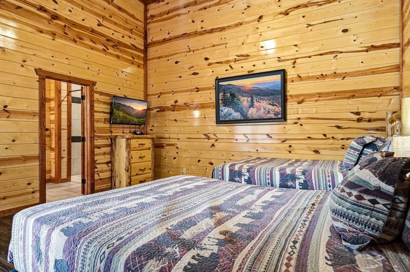 Wake up surrounded by warm knotty pine walls in this cozy cabin bedroom, where rustic charm meets modern comfort with your private TV.