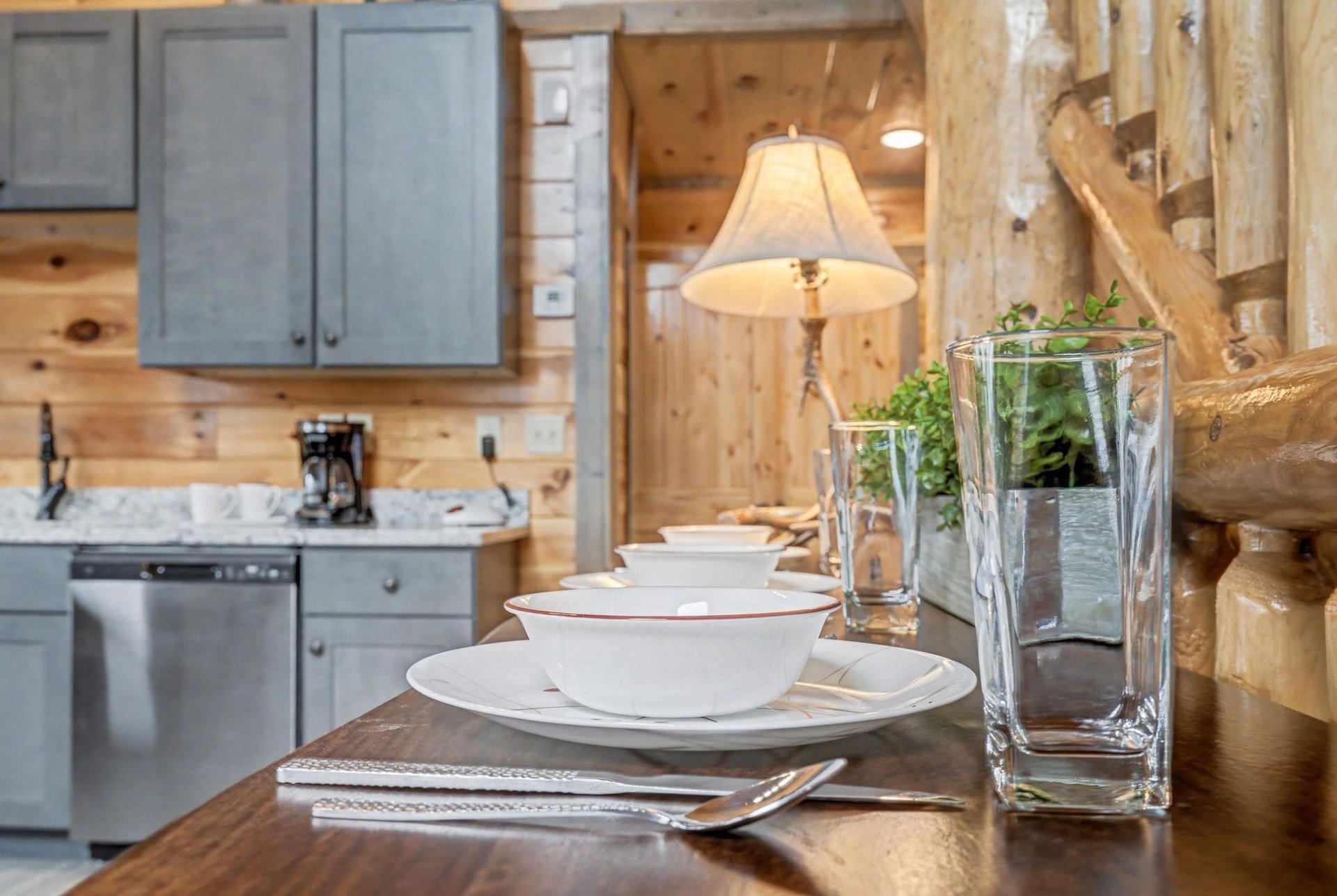Savor meals at your rustic dining table, where elegant place settings meet cozy cabin charm beneath warm pendant lighting.