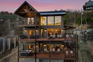A stunning mountain retreat featuring multiple levels of spacious decks and panoramic views, captured during the magical golden hour.