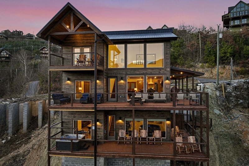 A stunning mountain retreat featuring multiple levels of spacious decks and panoramic views, captured during the magical golden hour.