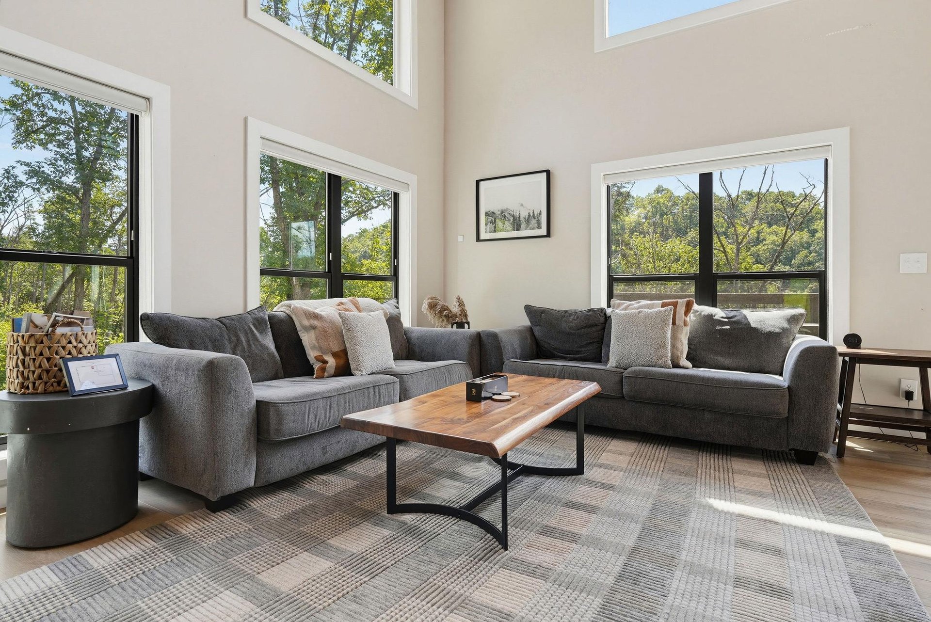 Settle into this bright, airy living space where towering windows frame lush treetop views. Your perfect spot to unwind with morning coffee or gather for an evening in.