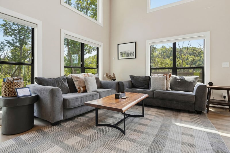 Settle into this bright, airy living space where towering windows frame lush treetop views. Your perfect spot to unwind with morning coffee or gather for an evening in.