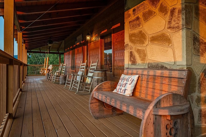 Charming covered porch with rustic wooden benches and rocking chairs invites you to relax. Perfect for morning coffee or evening conversations, with stone accents adding warmth to your mountain escape