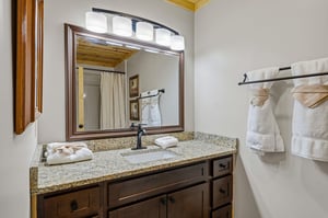 Step into your private bathroom, where crisp towels and a welcoming vanity await your arrival. Warm wood tones and soft lighting create a cozy retreat for your mountain getaway.
