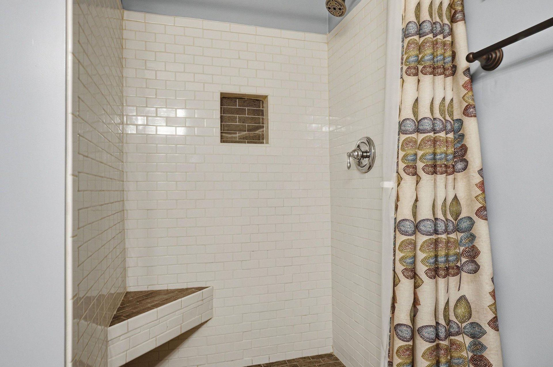 Step into your spalike shower with elegant subway tiles, a builtin corner bench for comfort, and a decorative niche for your essentials—perfectly designed for relaxation.