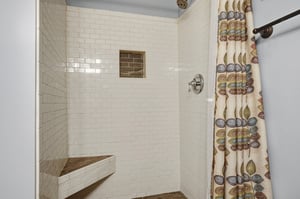 Step into your spalike shower with elegant subway tiles, a builtin corner bench for comfort, and a decorative niche for your essentials—perfectly designed for relaxation.