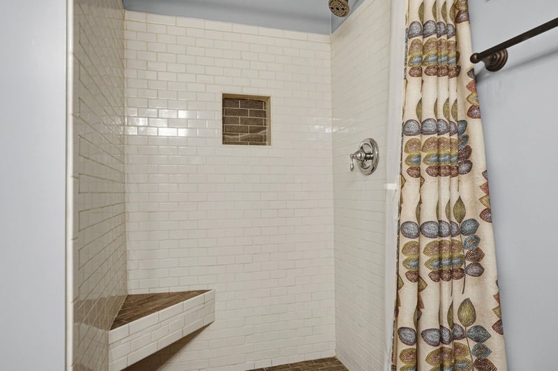 Step into your spalike shower with elegant subway tiles, a builtin corner bench for comfort, and a decorative niche for your essentials—perfectly designed for relaxation.