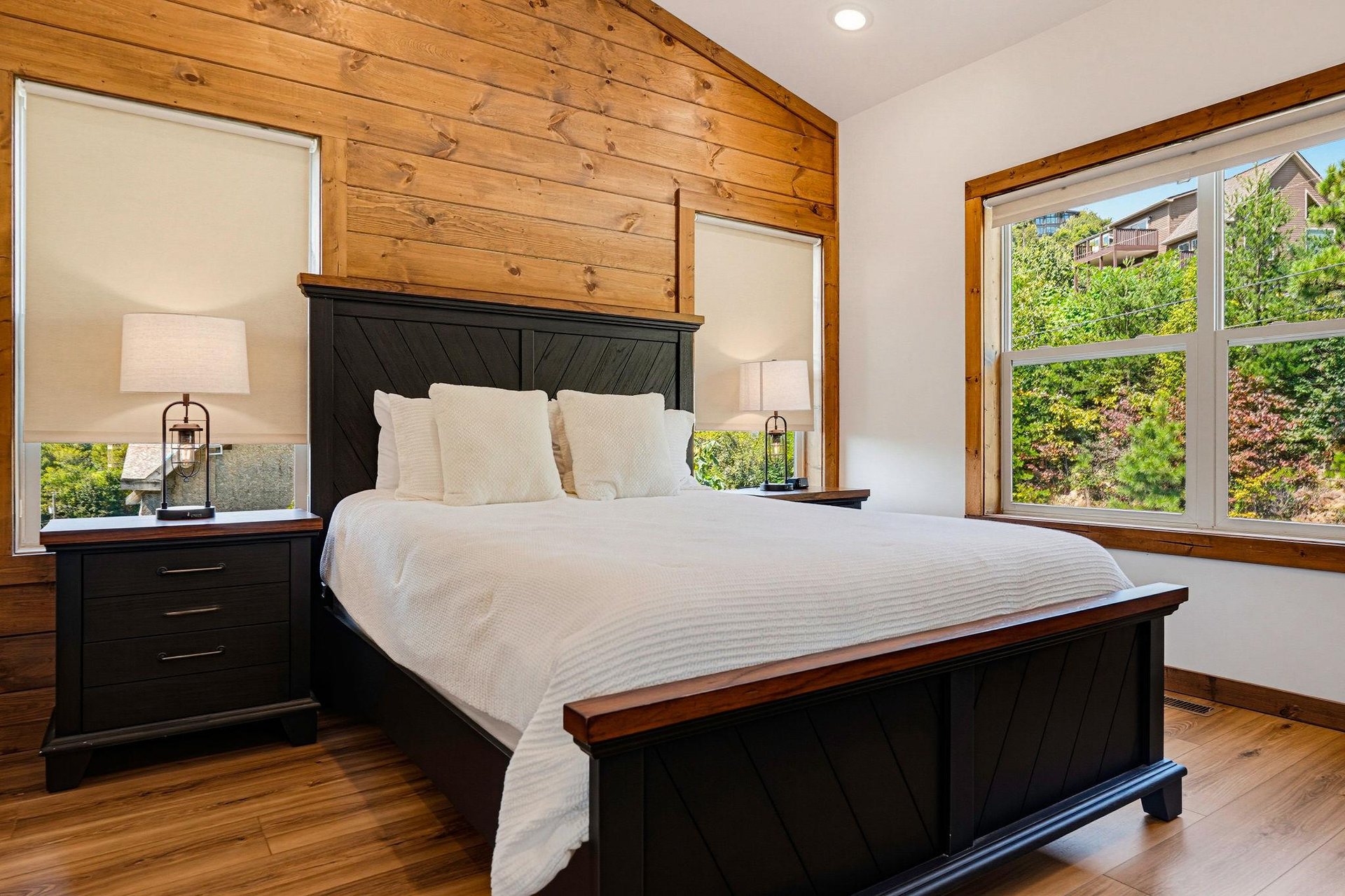 Sink into crisp white linens in your inviting bedroom, where warm wood paneling and garden views create a serene retreat after your mountain adventures.
