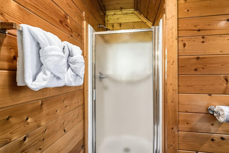Step into your private shower with warm wood paneling and crisp white towels waiting for you. The rustic charm and modern fixtures blend perfectly for your mountain getaway.