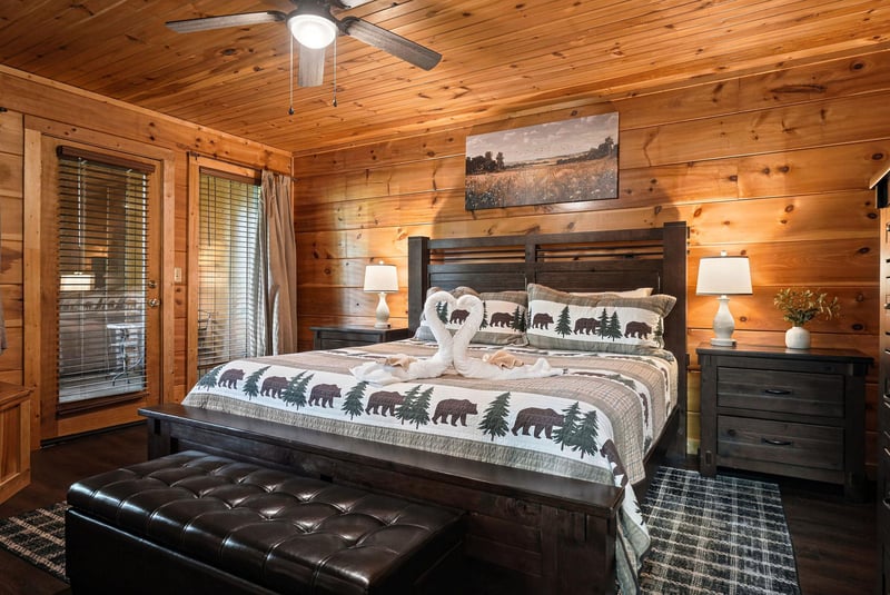 Relax in this cozy cabin bedroom with charming woodland bedding, warm wood walls, and soft lighting that welcomes you to unwind after your adventures.