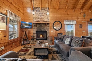 Unwind in your cozy living room with vaulted pine ceilings, a glowing stone fireplace, and rustic cabin charm that makes you feel right at home.