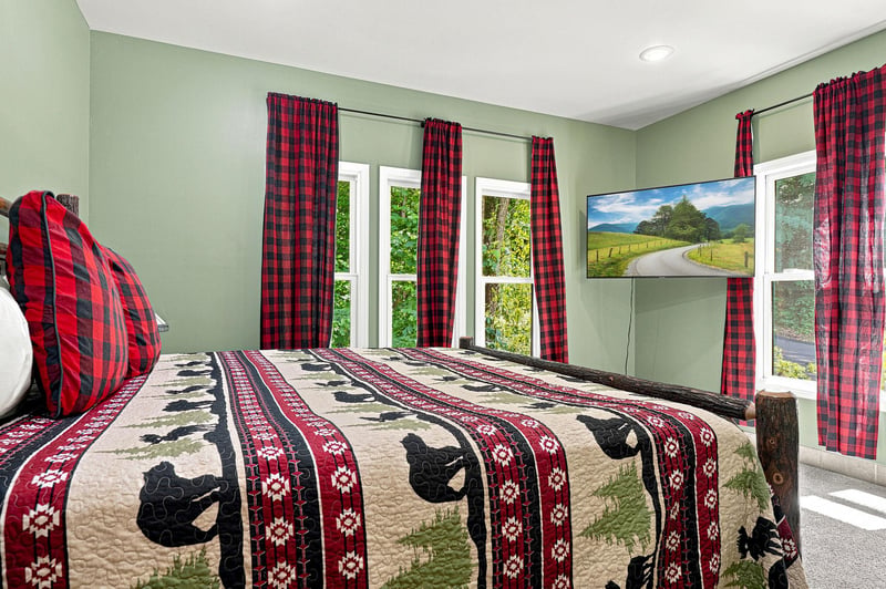 Settle into your cozy bedroom with rusticinspired décor, multiple windows framing lush greenery, and charming plaid accents that invite restful mountain escapes.
