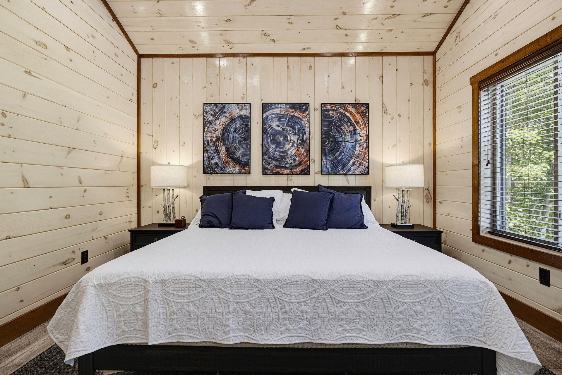 Slip into crisp white linens and let the peaceful woods outside your window lull you to sleep in this serene cabin bedroom.