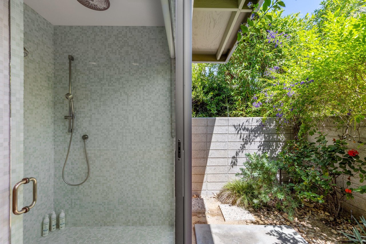 Standalone shower with its own sliding door to turn it into an indooroutdoor shower.