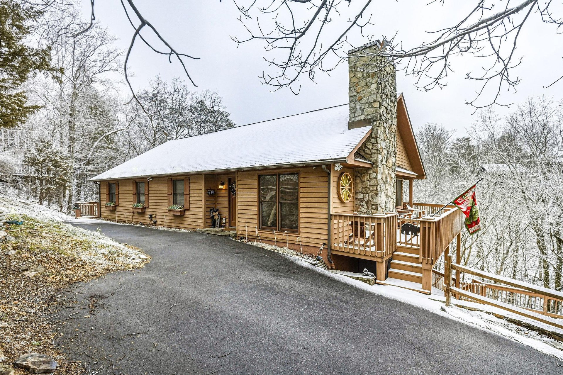 Charming log cabin nestled among snowdusted trees, featuring a stone chimney and welcoming deck for your mountain getaway.