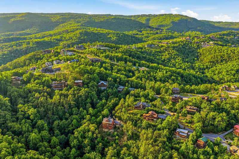 Aerial view of vacation rental properties nestled among lush forested mountains, showcasing the serene natural surroundings and peaceful mountain landscape of the area.