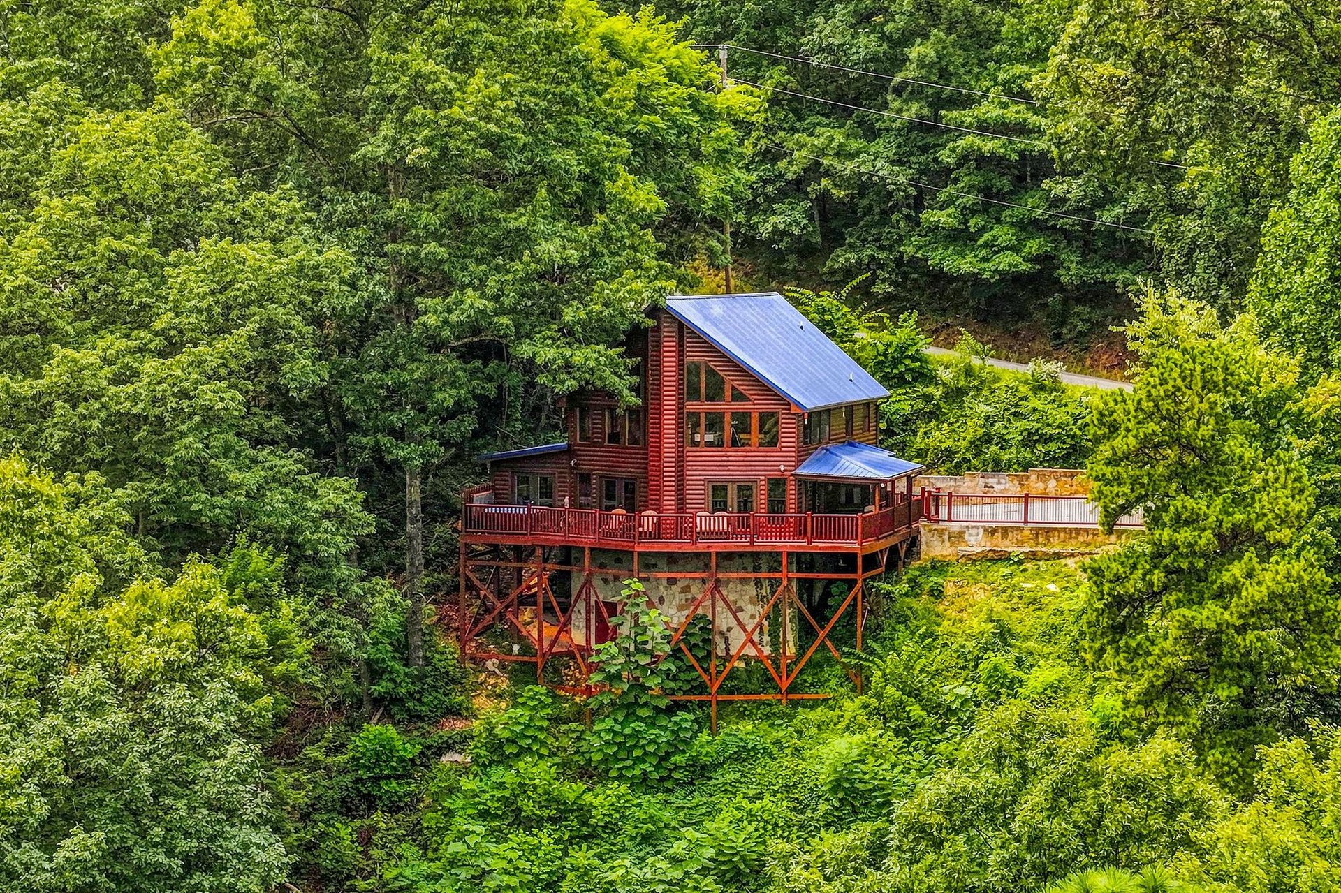 A distinctive red cabin nestled among lush green forest on an elevated deck, offering a peaceful natural setting and unique architecture.
