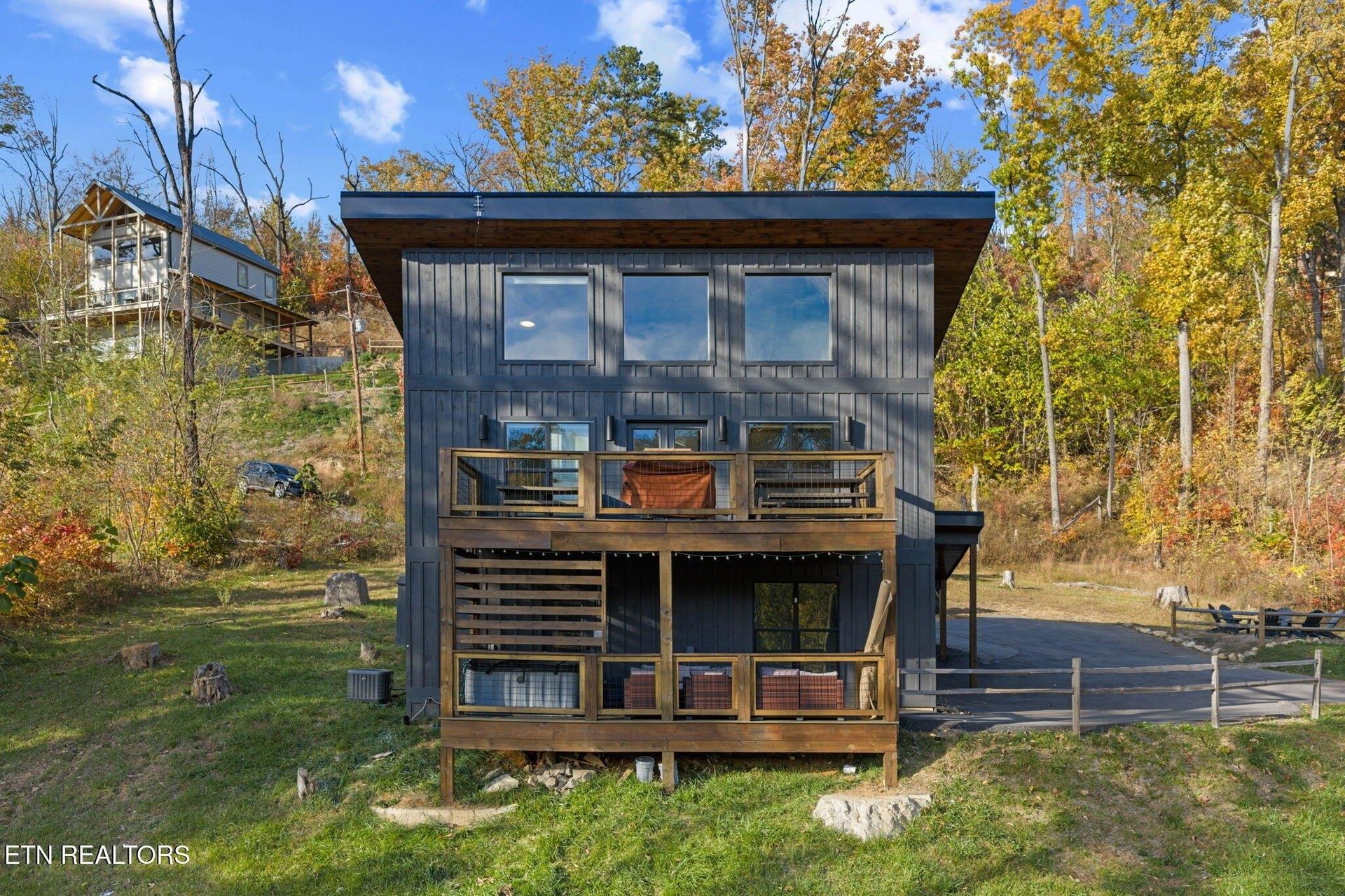 A striking modern cabin nestled among vibrant fall foliage with colorful leaves painting the surrounding landscape in warm autumn hues.