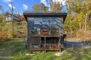 A striking modern cabin nestled among vibrant fall foliage with colorful leaves painting the surrounding landscape in warm autumn hues.