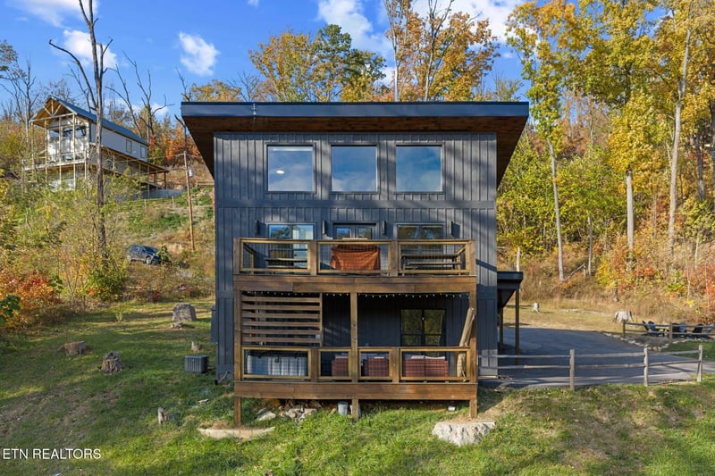 A striking modern cabin nestled among vibrant fall foliage with colorful leaves painting the surrounding landscape in warm autumn hues.