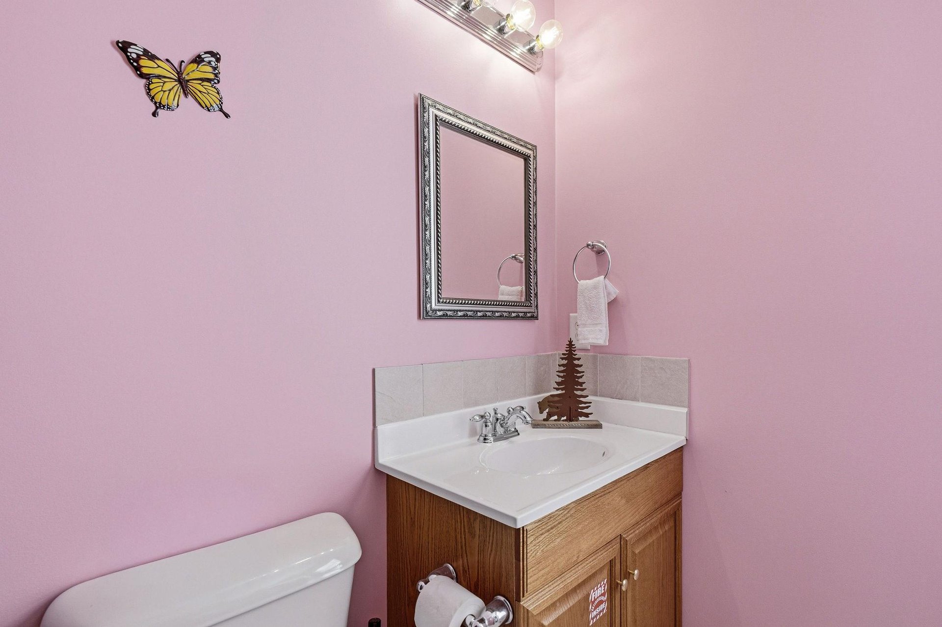 Step into your charming powder room featuring soft pink walls, elegant vanity, and whimsical butterfly decor that creates a delightful space.