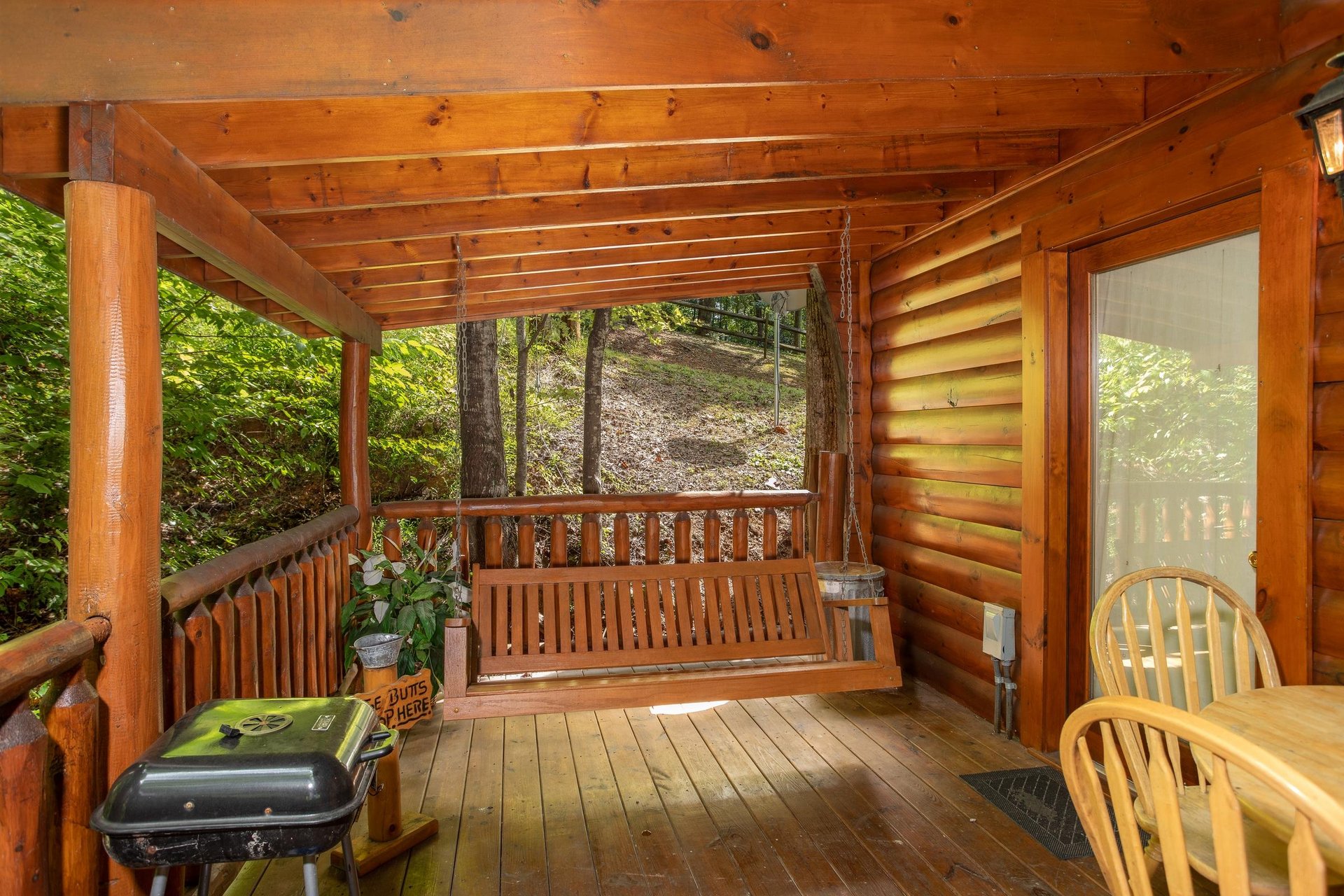Covered porch with swing, dining space, and a charcoal grill at Dreams Do Come True, a 1bedroom cabin rental located in Pigeon Forge