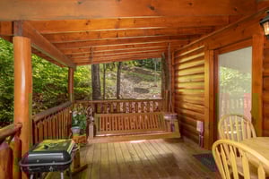 Covered porch with swing, dining space, and a charcoal grill at Dreams Do Come True, a 1bedroom cabin rental located in Pigeon Forge
