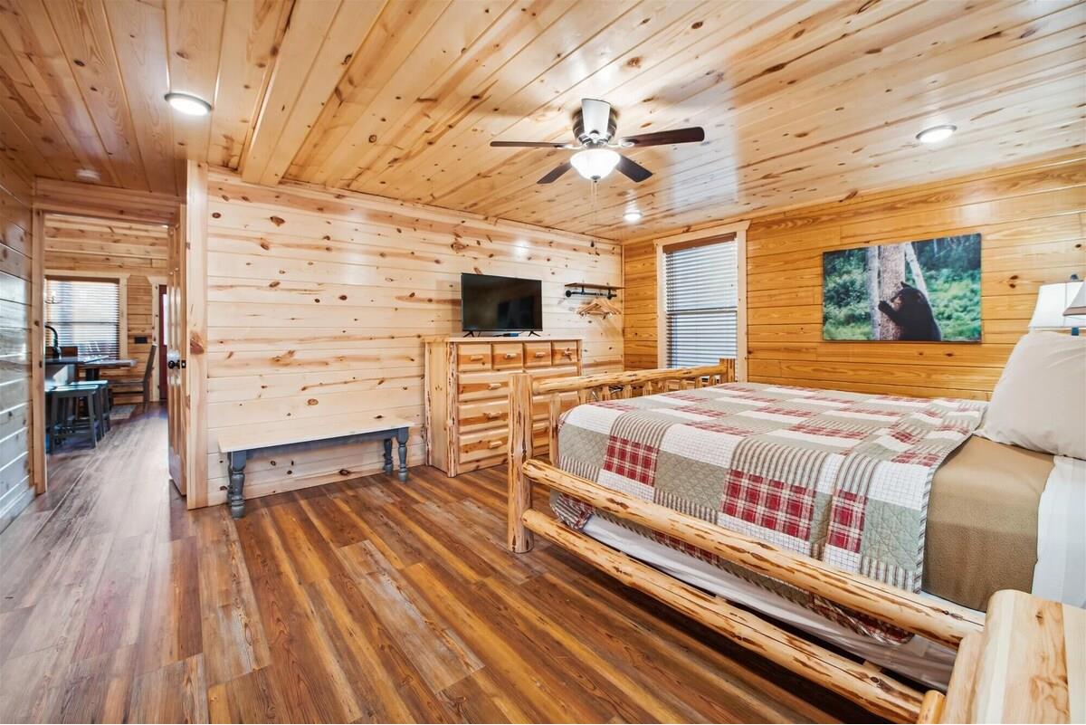 Cozy rustic bedroom with log bed, warm wood, TV, and nature artwork creates your perfect mountain retreat sanctuary.