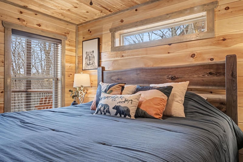 Sink into this rustic bedrooms cozy embrace with its handcrafted wooden headboard, soft linens, and peaceful forest views through your window.