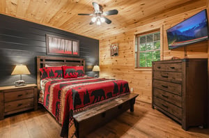 Your cozy cabin bedroom blends rustic pine walls with stylish black shiplap, creating a warm retreat where youll drift off under the glow of bedside lamps and a ceiling fan.