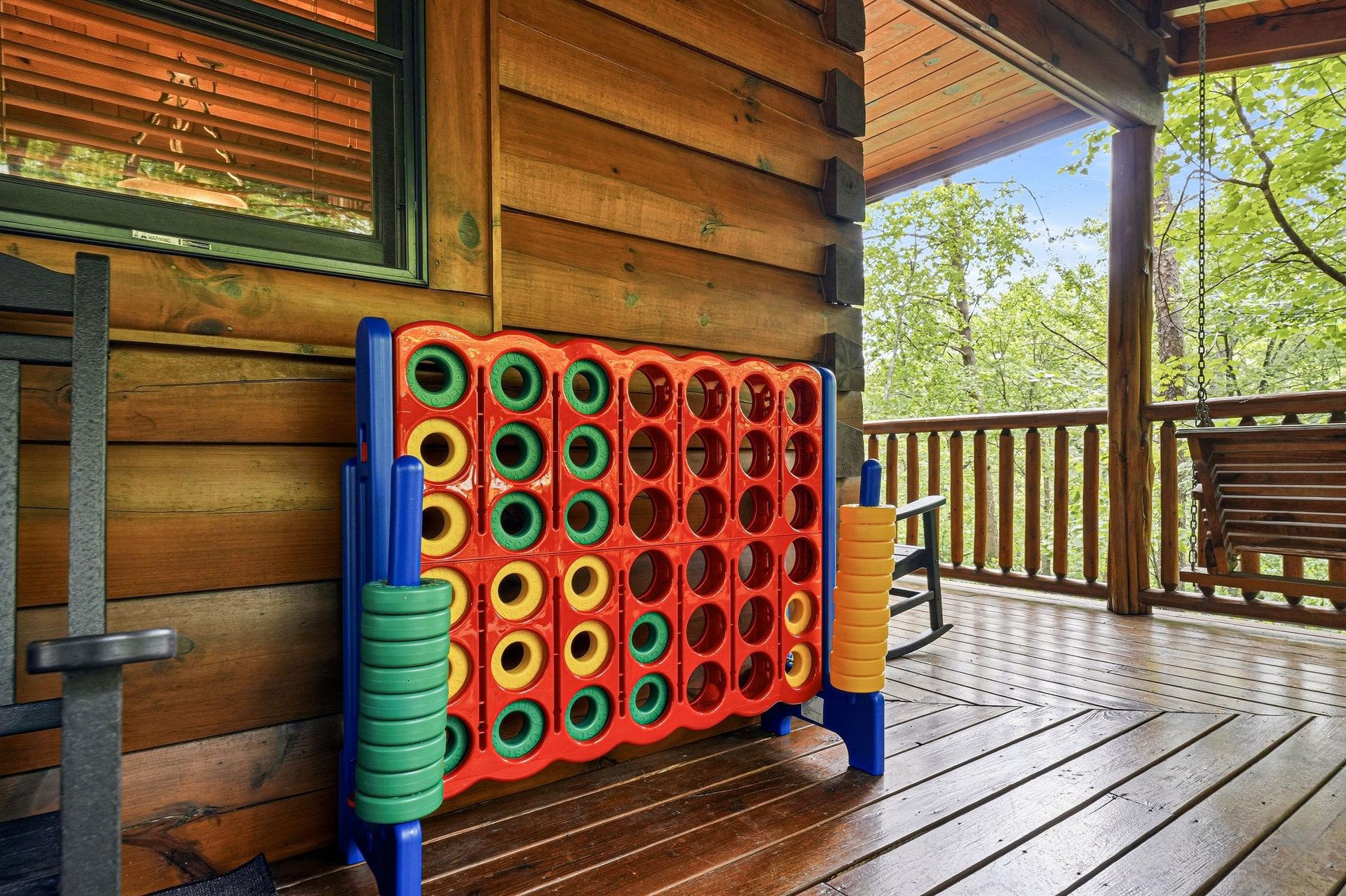 A colorful oversized Connect Four game awaits on your private deck, perfect for family fun surrounded by peaceful forest views and fresh mountain air.