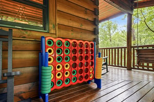 A colorful oversized Connect Four game awaits on your private deck, perfect for family fun surrounded by peaceful forest views and fresh mountain air.