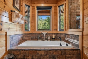 Sink into pure relaxation in your private jetted tub, surrounded by warm wood and natural light streaming through the windows framing lush treetop views.