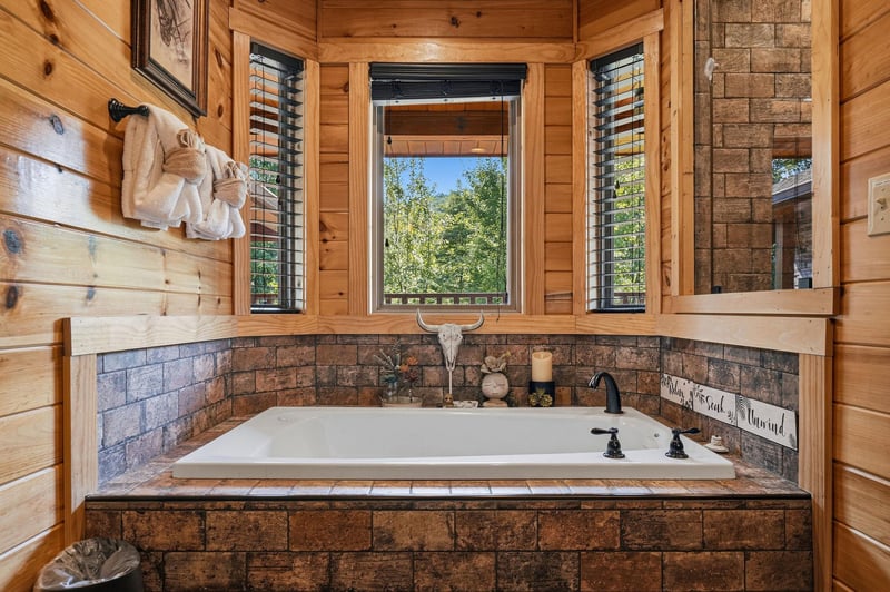 Sink into pure relaxation in your private jetted tub, surrounded by warm wood and natural light streaming through the windows framing lush treetop views.
