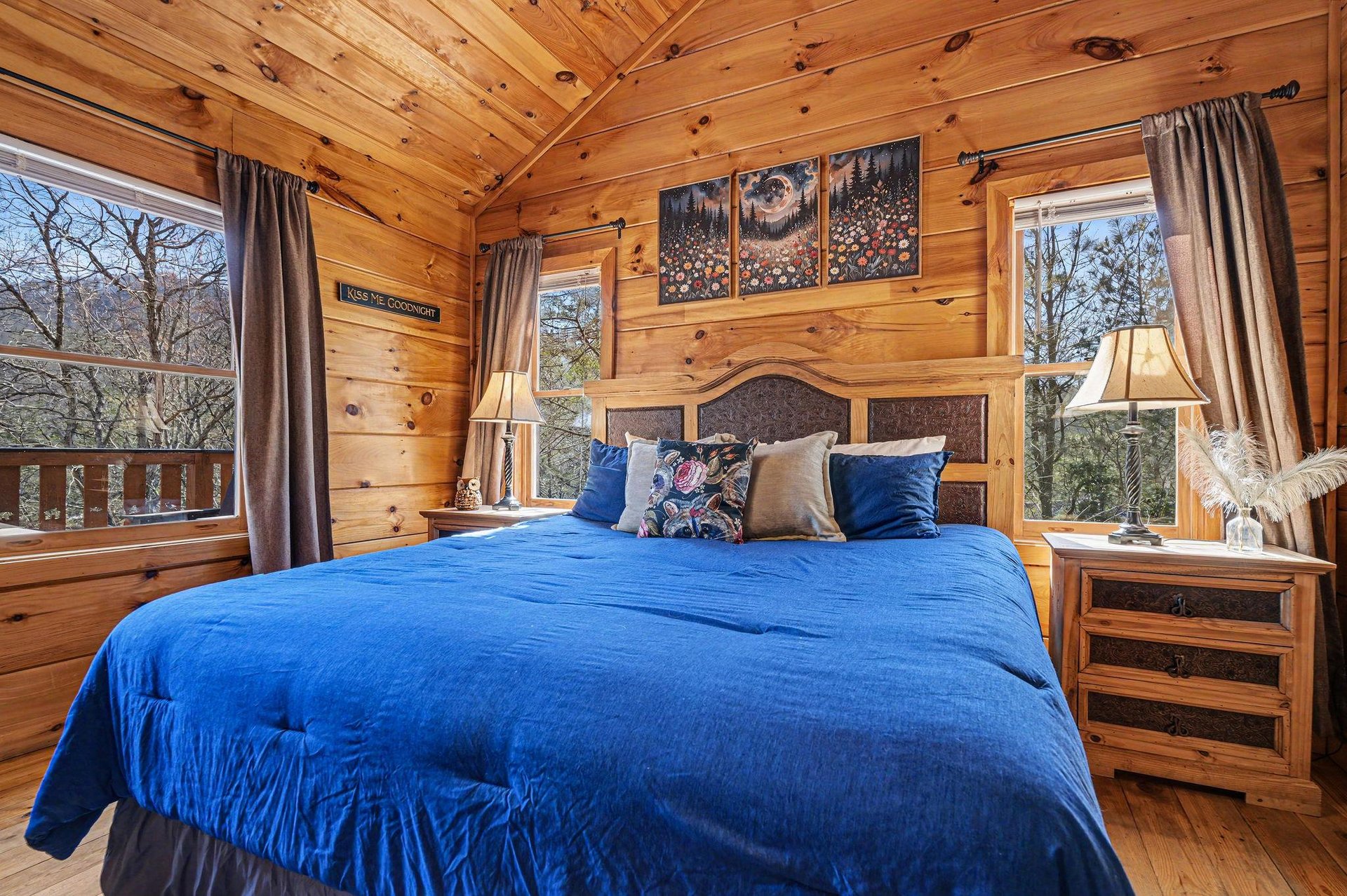 Cozy up in your rustic bedroom with rich blue linens and warm wood walls while forest views frame your mountain retreat.