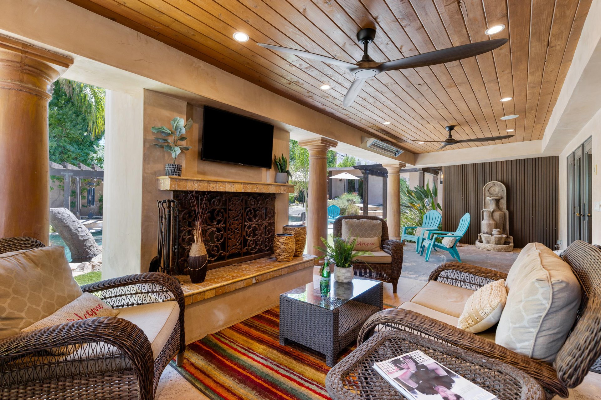 Incredible covered patio space with outdoor fireplace, flatscreen TV, ample seating, dining space, and outdoor kitchen with BBQ.