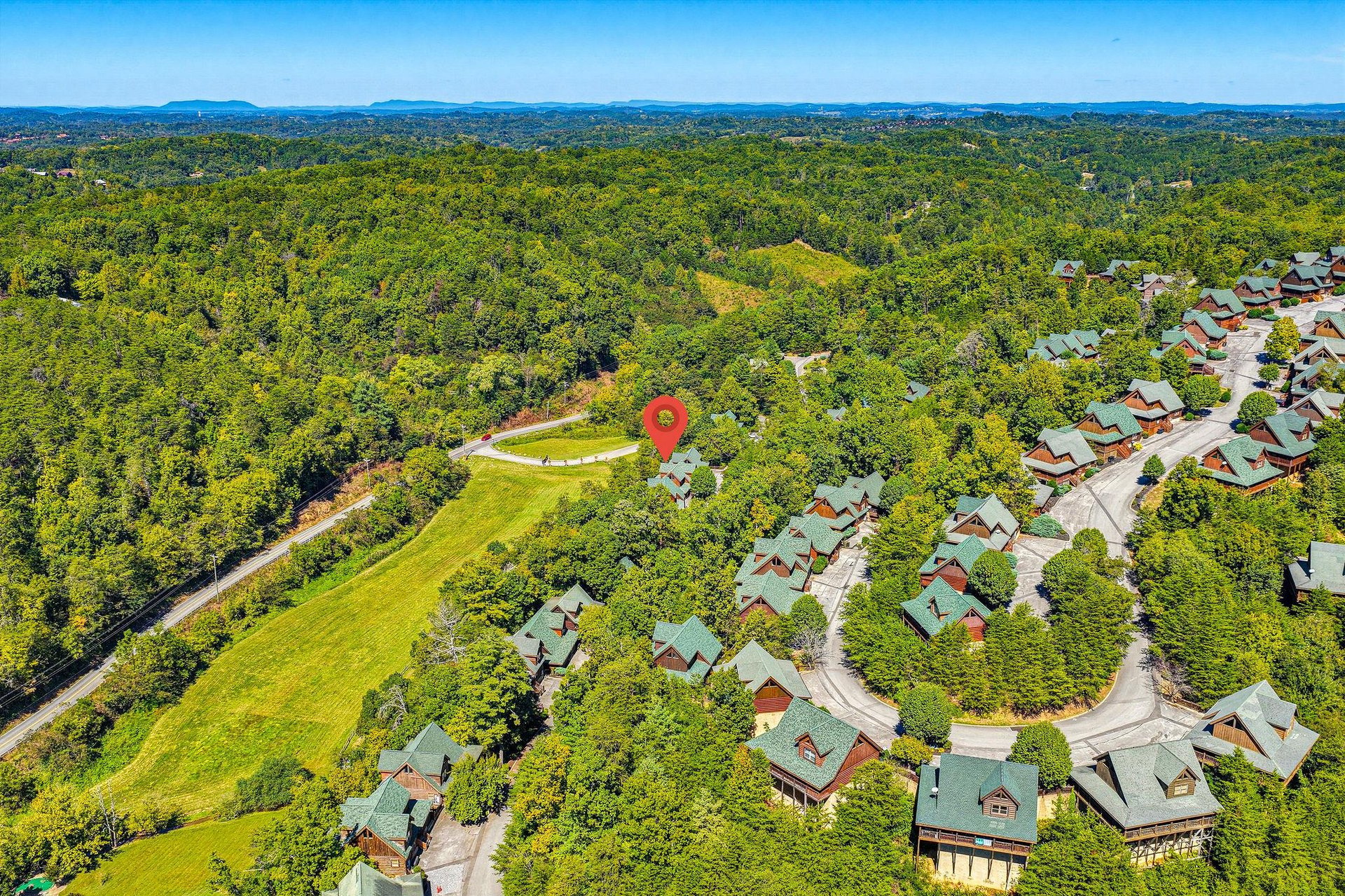 A scenic mountain resort community nestled among dense forest with distant mountain ranges framing the horizon.