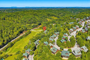 A scenic mountain resort community nestled among dense forest with distant mountain ranges framing the horizon.