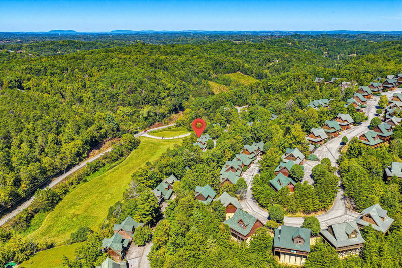 A scenic mountain resort community nestled among dense forest with distant mountain ranges framing the horizon.