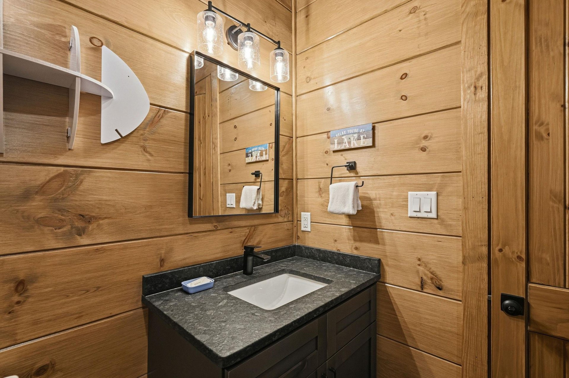 Step into your rusticchic bathroom featuring warm pine walls, granite countertops, and thoughtful lighting that creates the perfect lakehouse retreat atmosphere.