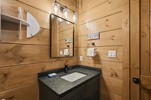 Step into your rusticchic bathroom featuring warm pine walls, granite countertops, and thoughtful lighting that creates the perfect lakehouse retreat atmosphere.