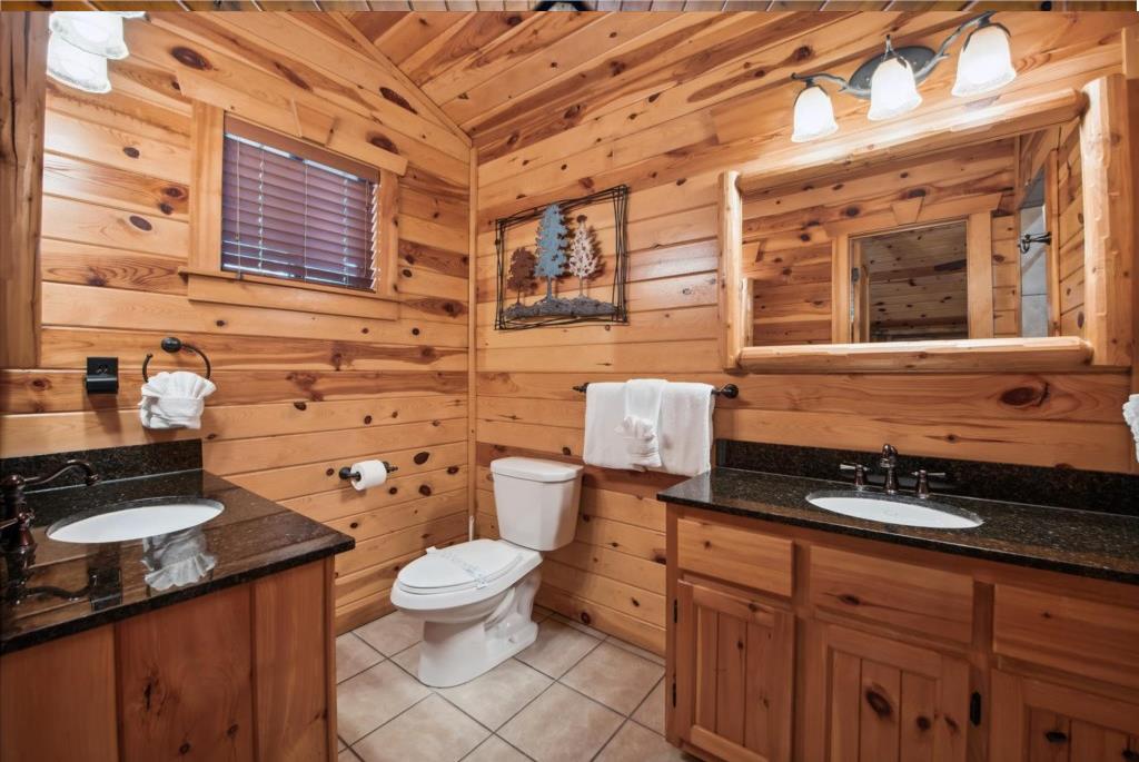Step into your private rustic bathroom where warm cedar walls and granite counters create a cozy mountain retreat atmosphere.
