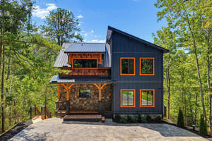 A striking modern mountain retreat featuring bold architectural lines, warm wood accents, and expansive windows framed by lush forest surroundings.