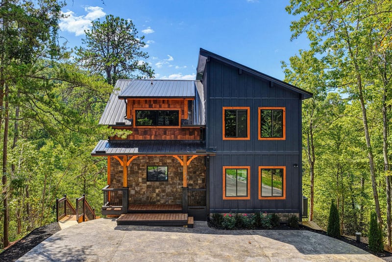 A striking modern mountain retreat featuring bold architectural lines, warm wood accents, and expansive windows framed by lush forest surroundings.