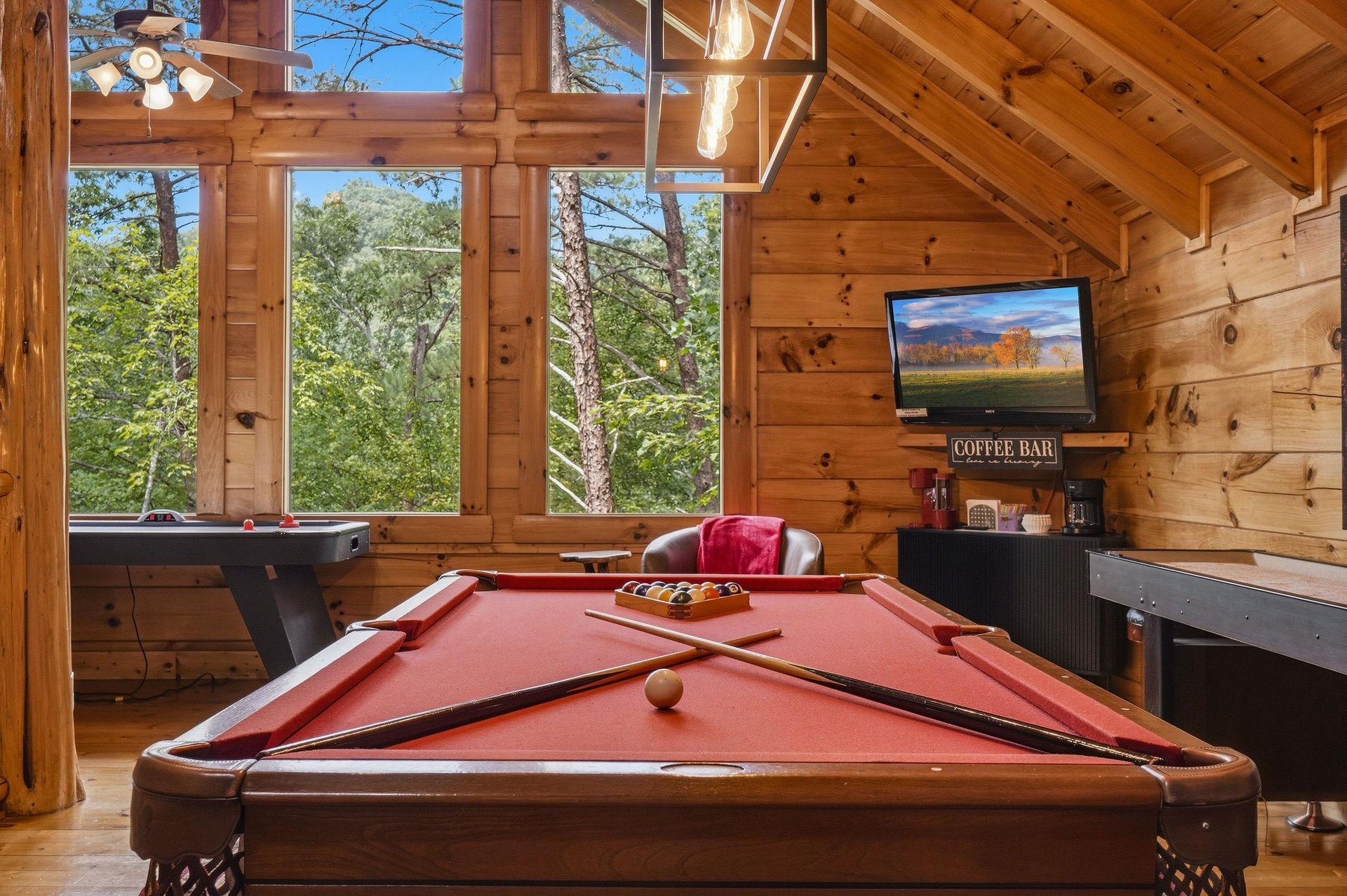 Your own game room features a fullsize pool table and arcade fun, framed by towering windows that bring the forest inside—perfect for friendly competition surrounded by nature.