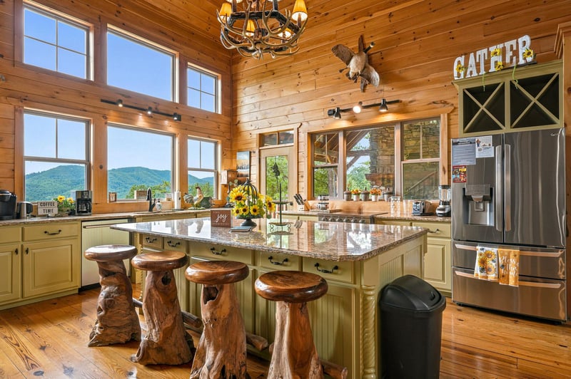 Gather in this stunning rustic kitchen featuring sweeping mountain views, a spacious island with unique log stools, and all the warmth of natural wood surrounding you.