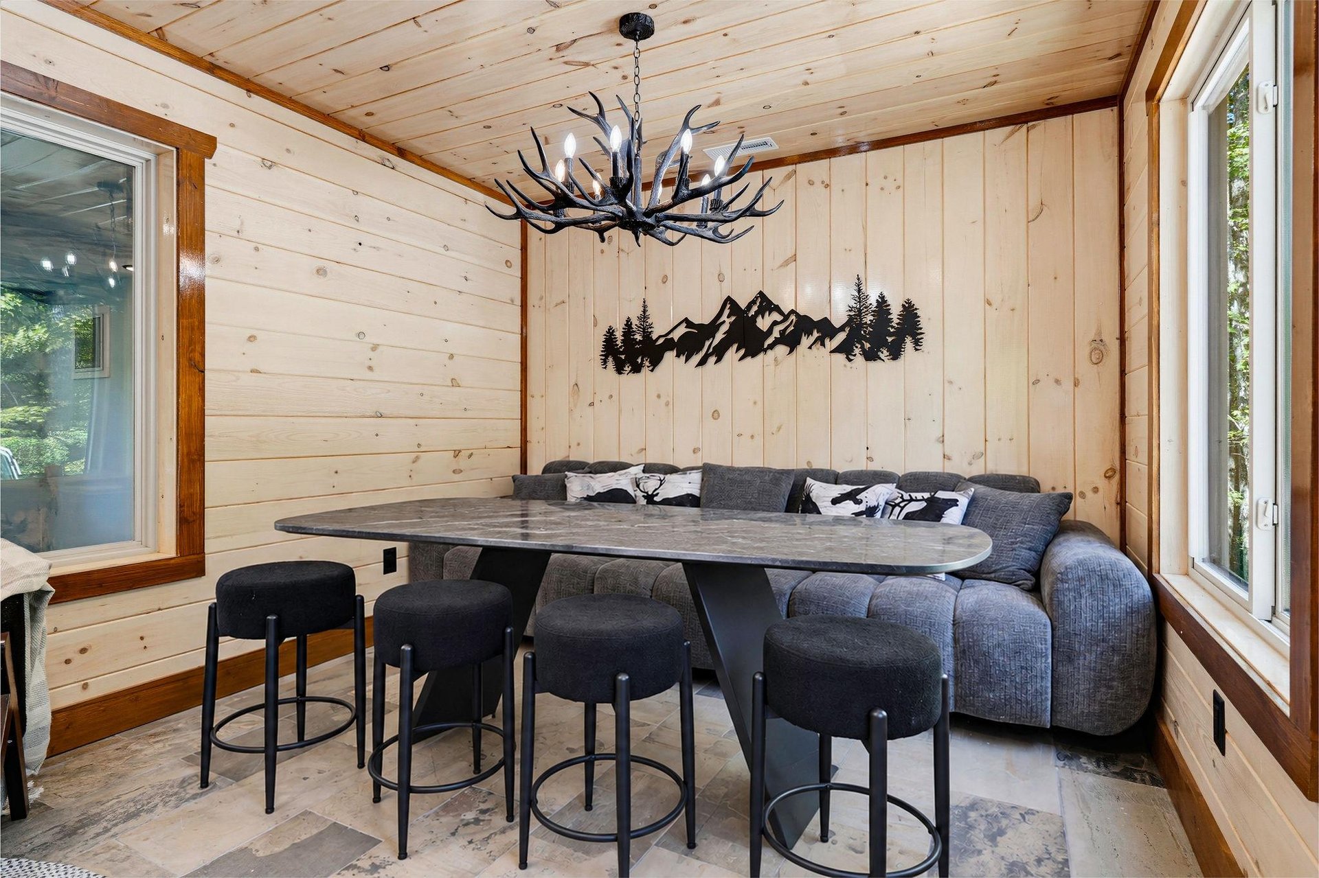 Gather around this cozy alpineinspired dining nook, where rustic wood paneling meets mountain charm. Your meals here feel like evenings in a cabin retreat, complete with antler chandelier and views o